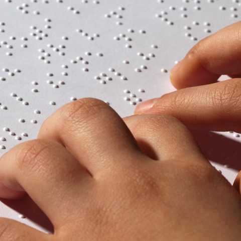 hands reading a page of braille