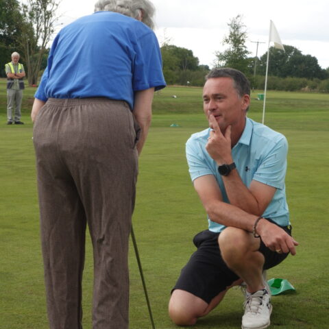 A member holding a golf club, stood in front of Mark, York Golf Club's professional.