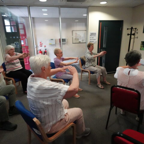 MySight York's Tai Chi group taking part in the session. The instructor is on the TV screen at the front, via Zoom.