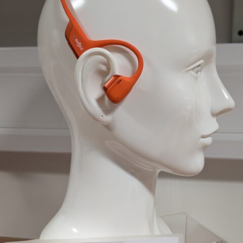 white dummy head wearing bright orange headphones